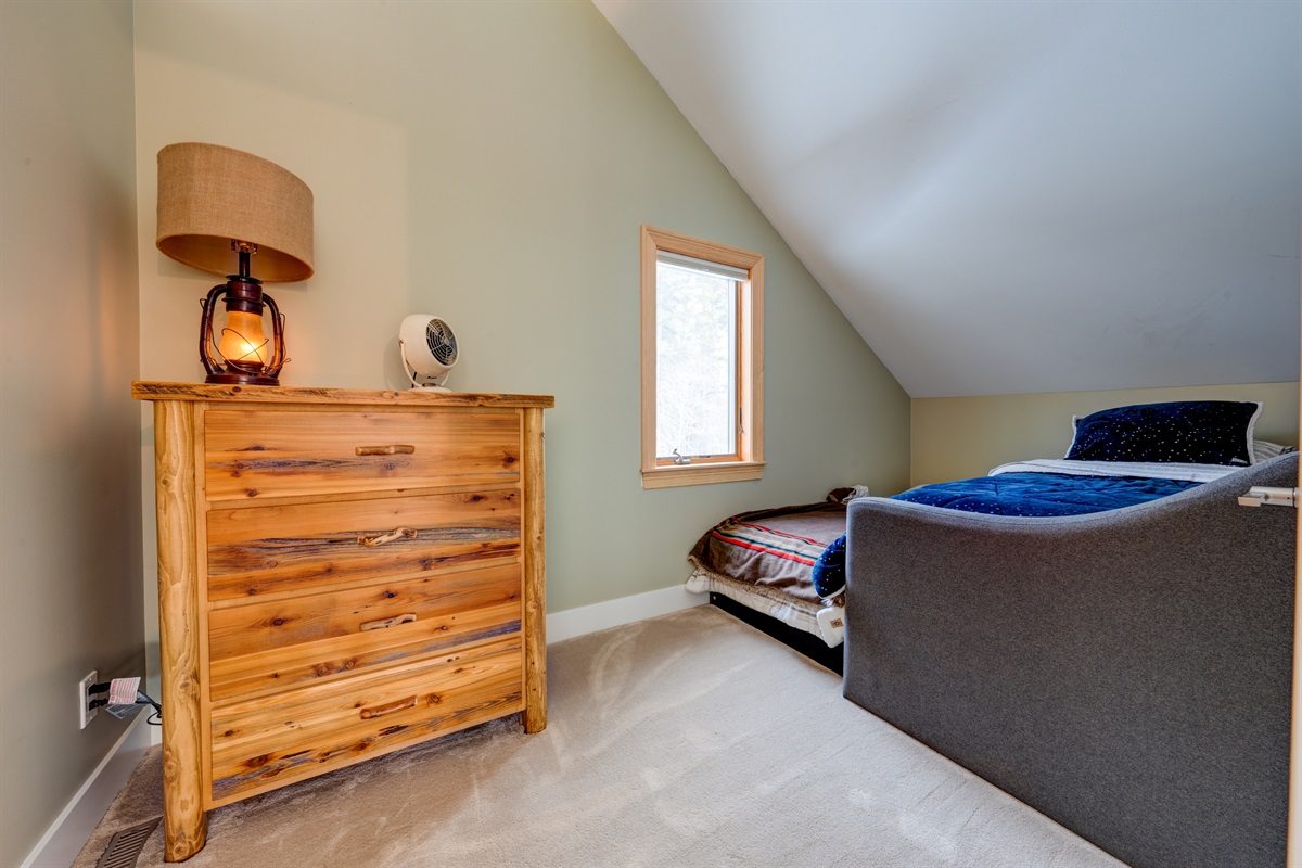 2nd Floor bedroom with trundle bed, 2 twin mattresses, and a large dresser. Loft bedroom with door and privacy, though one wall is open to the vaulted ceiling.