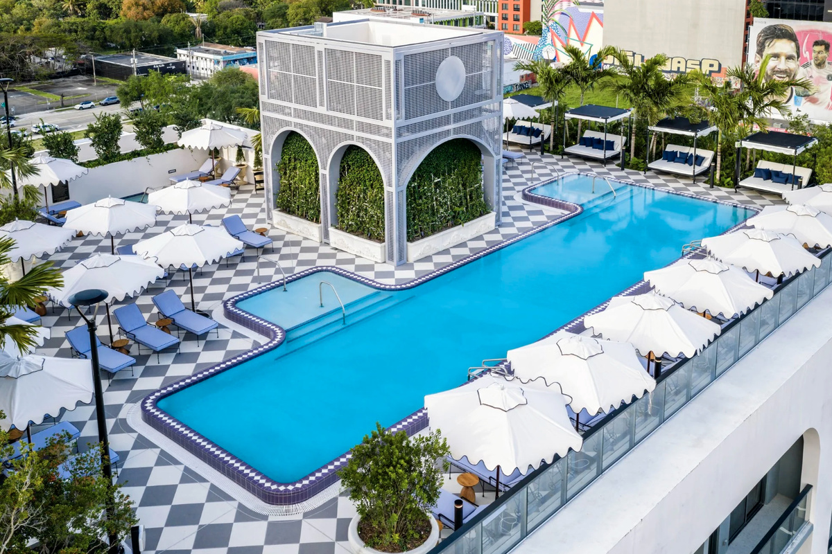 A resort-style pool framed by arched architecture, private cabanas and a graphic stone deck - a true urban oasis.