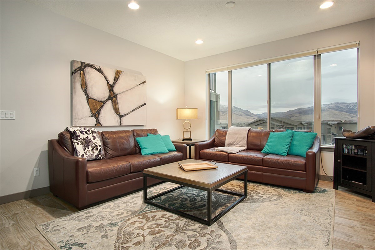 An inviting living space with rich leather seating and panoramic vistas, blending modern comfort with the natural beauty of the surrounding landscape.