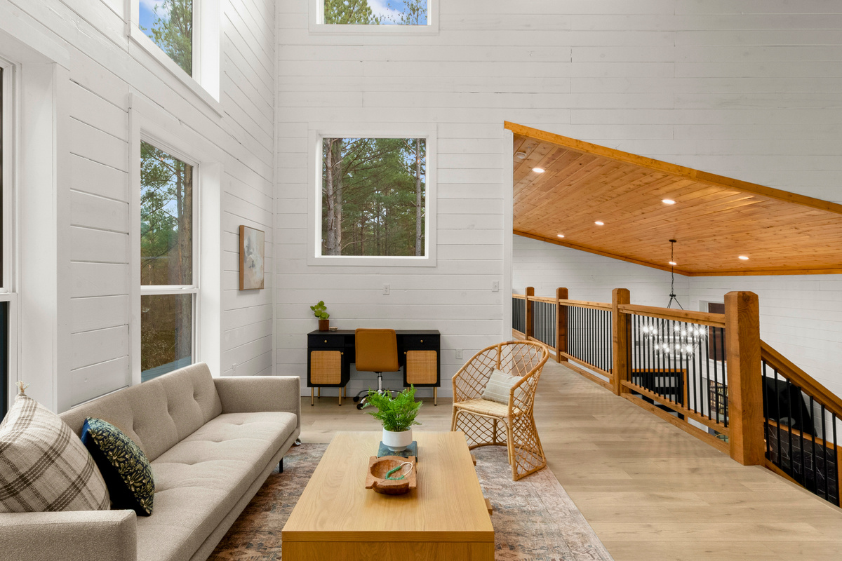 This space exudes contemporary elegance, with its high vaulted ceilings and expansive windows that frame the surrounding forest and allow natural light to flood the space.