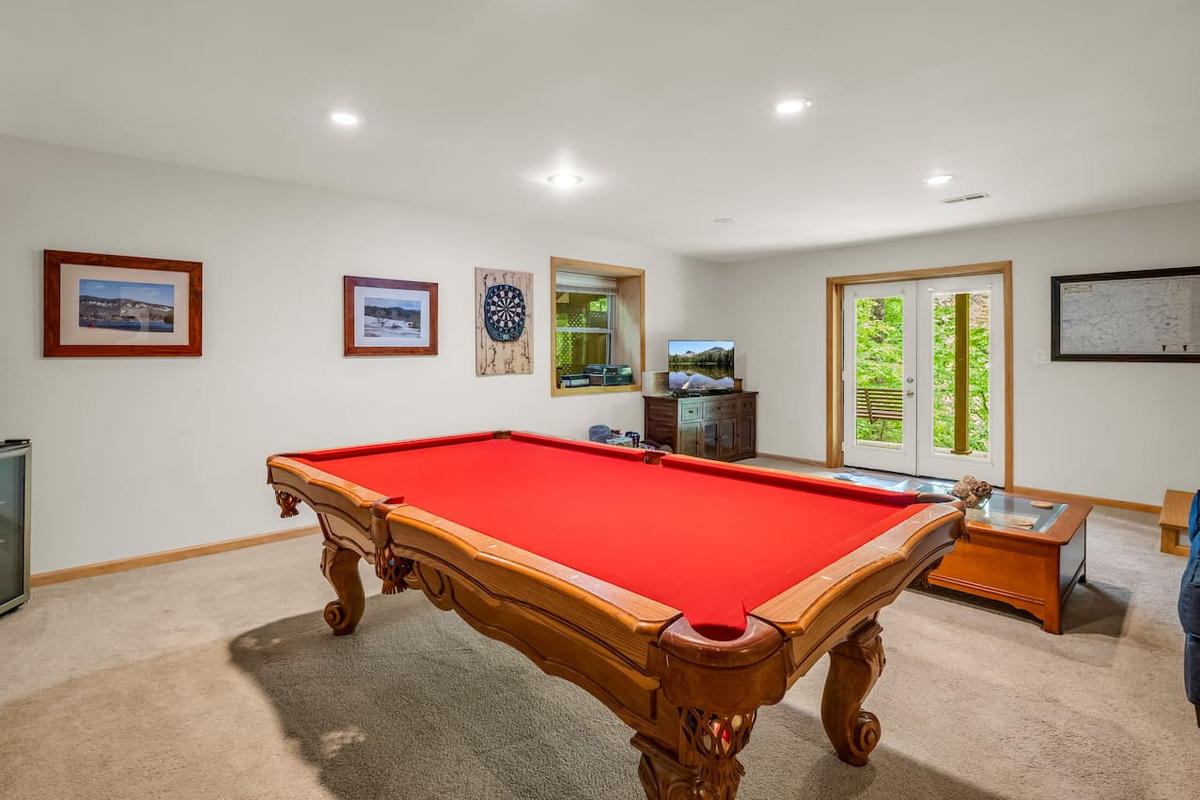 Basement with pool table, seating area, board games, and French doors leading to back patio area with swing, hot tub, and outdoor seating