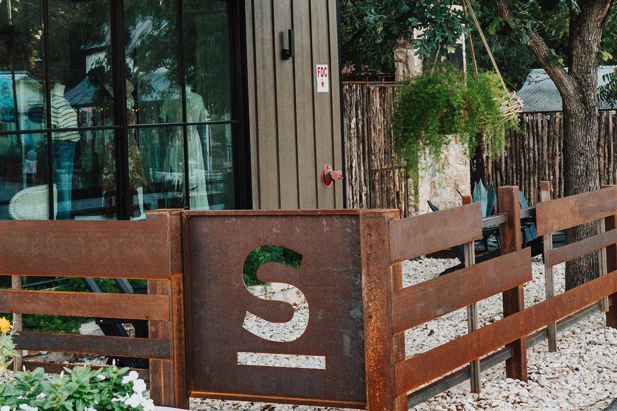 Hill Country stone and corral-style fencing carry modern Western design through Gaines Ranch on the Square — character built into every detail.