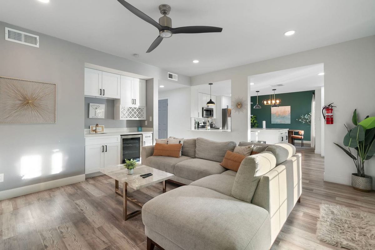 Spacious open-concept living area with modern kitchen, comfortable seating, and forest green accent wall.