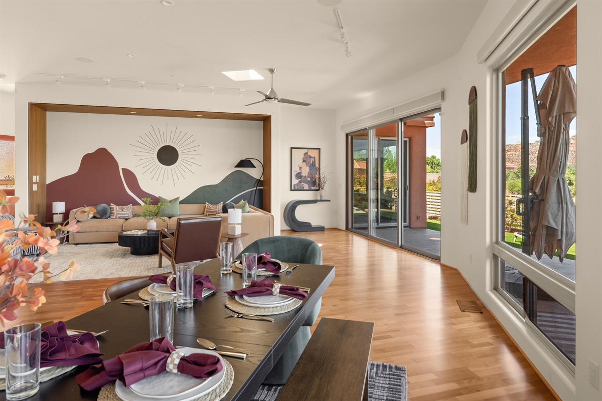 The open floor plan flows effortlessly from the elegant dining space into the sunlit living room, featuring striking custom murals and direct patio access.