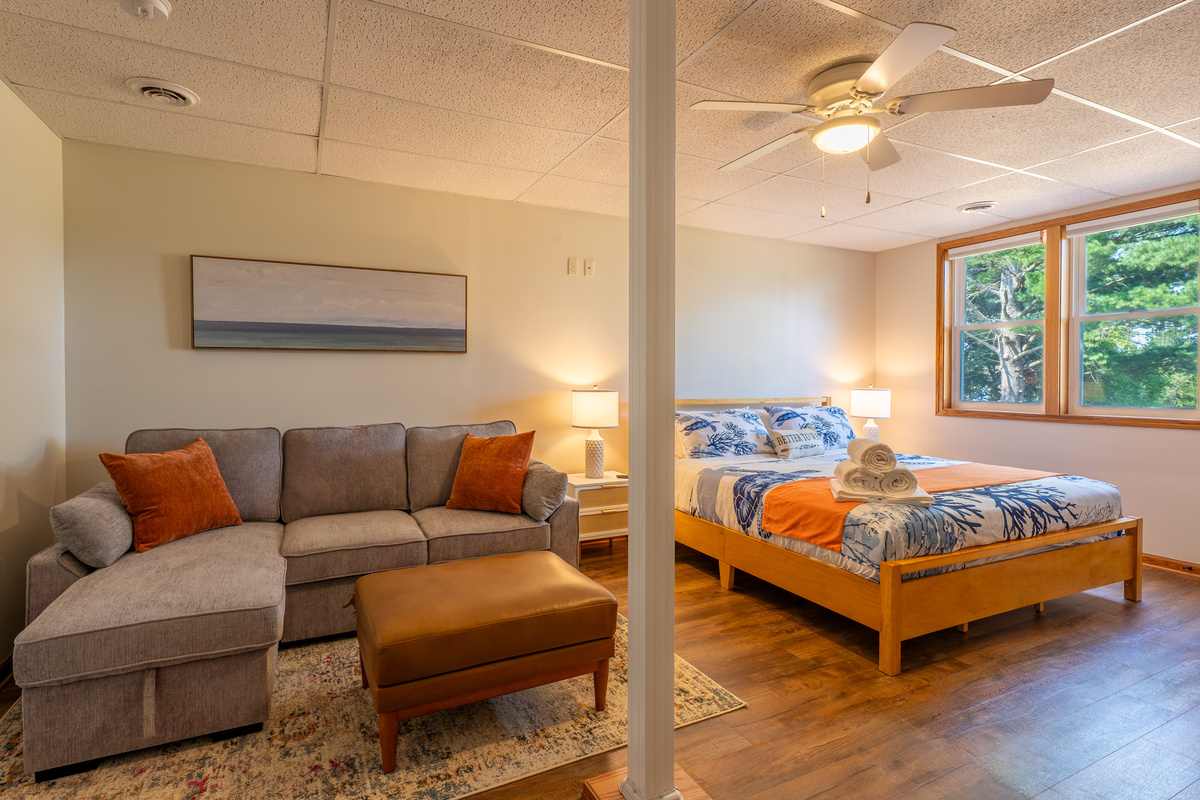 The flex room doubles as a 5th bedroom or a private lounge. It features a king bed, a queen sleeper sofa, and a full-size sleeping futon (not pictured), with its own 65" Smart Roku TV and direct access to the lower-level amenities