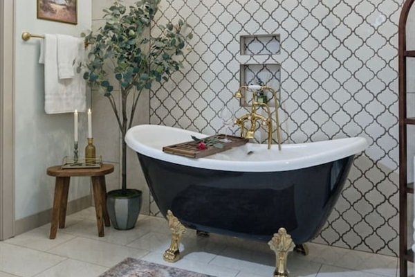Bright and elegant bathroom featuring a statement clawfoot tub, gold fixtures, and a warm, inviting spa-like atmosphere
