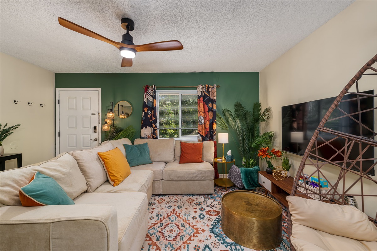 The cozy living room with a 55" smart TV, plush sectional couch, and cozy hammock chair.