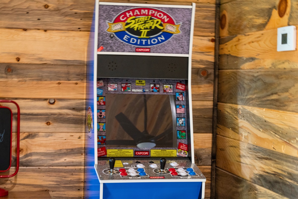 An arcade game machine featuring "Champion Street Fighter II Edition" in a cozy wooden cabin corner.