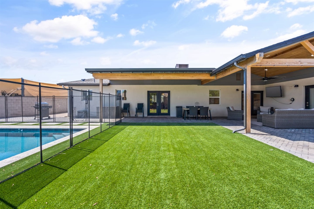 Outdoor living area with shaded lounge space, fire pit, and a clear view toward the pool.