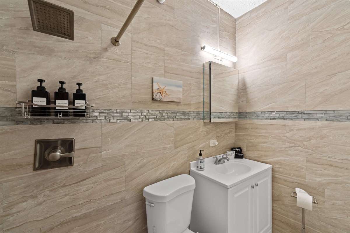 The apartment bathroom has a walk in shower with a rain shower head.