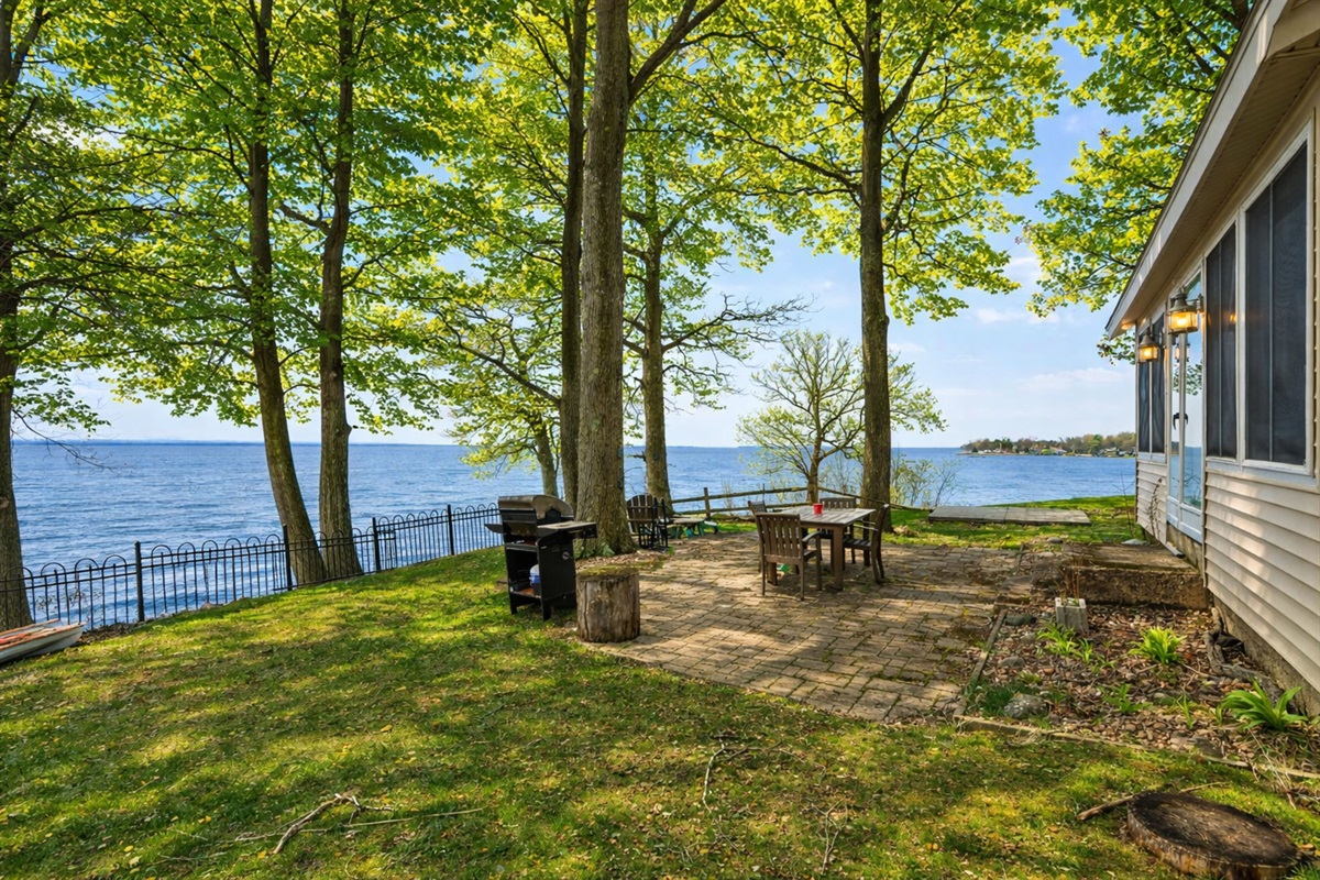 Enjoy outdoor dining by the lake with this charming patio setup, perfect for grilling and watching the sunset.