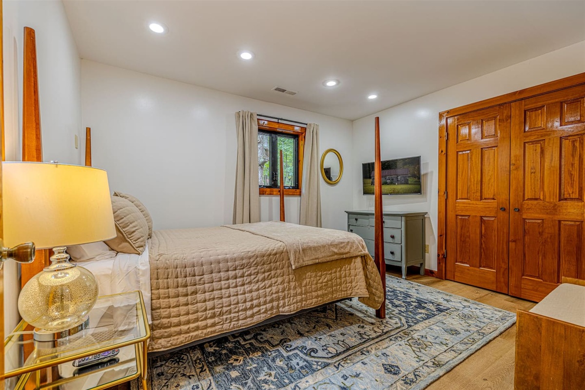 Blending classic design with modern amenities, this upstairs queen bedroom offers a charming four-poster bed, in-room entertainment, and ample storage.