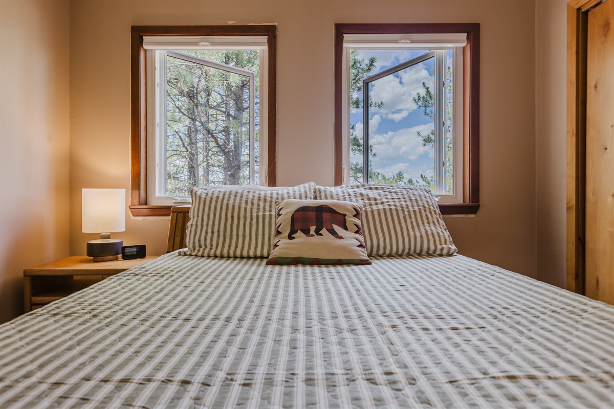 Upstairs queen bedroom with wide mountain views and soft, modern touches.