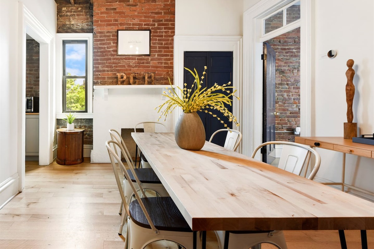 Gather around a spacious dining area featuring a long table, six stylish chairs, and an extra cushioned seat. With its simple yet elegant design, this room offers the perfect setting for shared meals, laughter, and unforgettable moments.