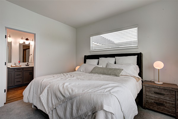 Relax in the serene master bedroom featuring a comfortable king-size bed, soft linens, and cozy pillows. Includes nightstands, lamps, walk-in closet, and full-length mirror for added comfort. 