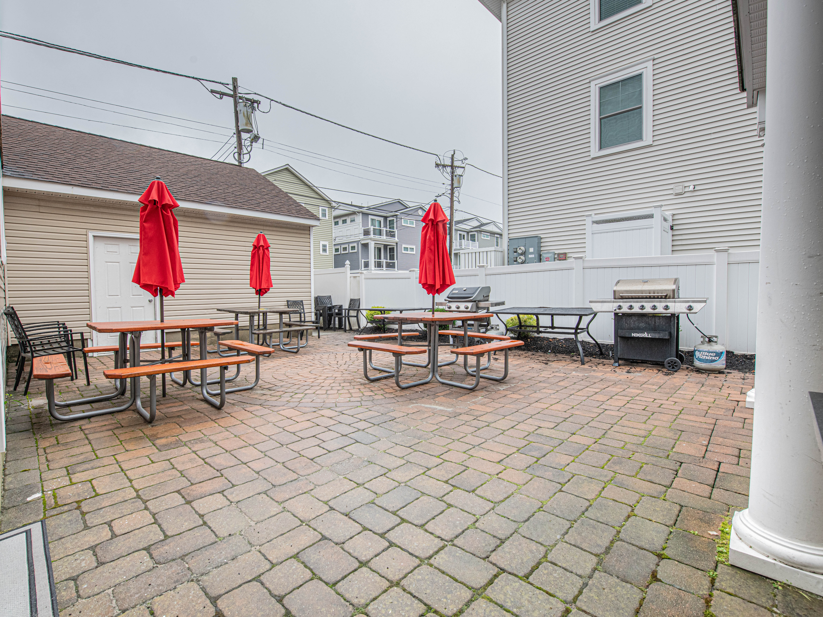 Outdoor Paver Patio with Picnic Tables, Red Umbrellas, and Grill
