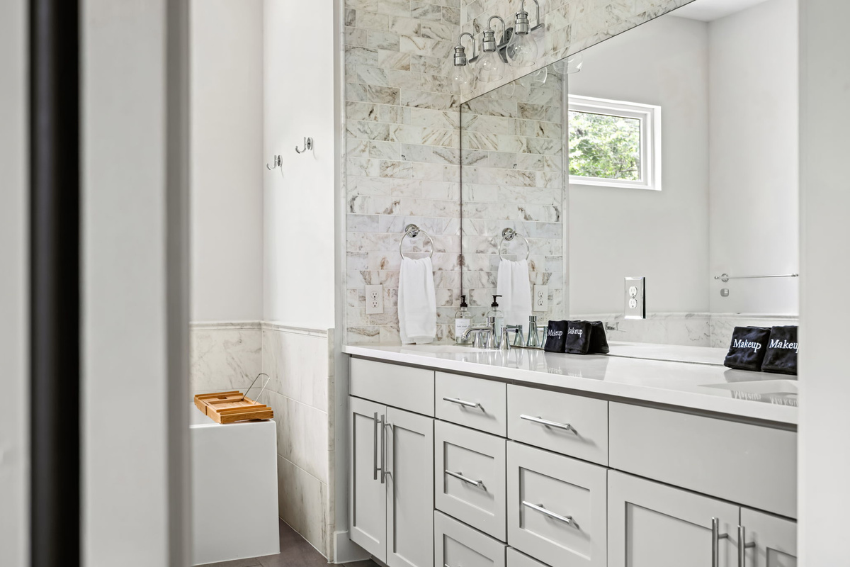 Sleek vanity nook with marble backsplash and ample storage — a functional yet elegant corner of this spacious bathroom.