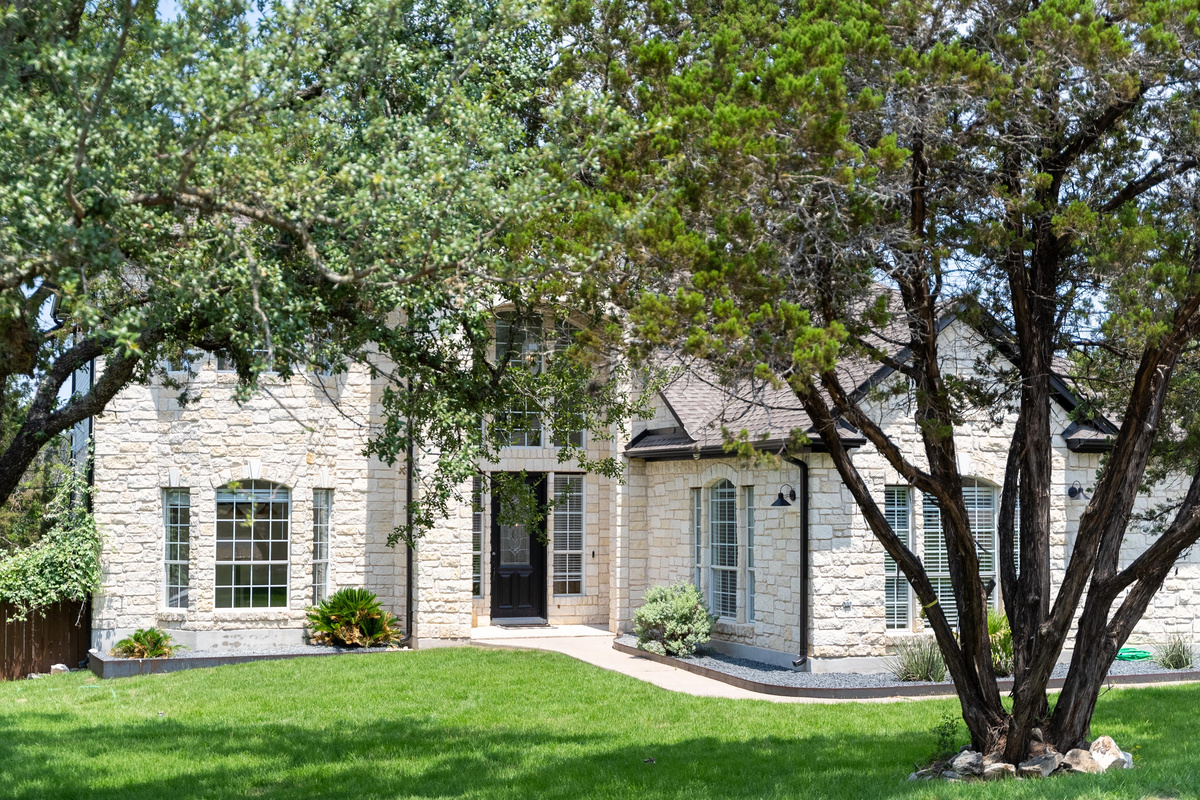 Mature oak trees frame the charming stone façade.