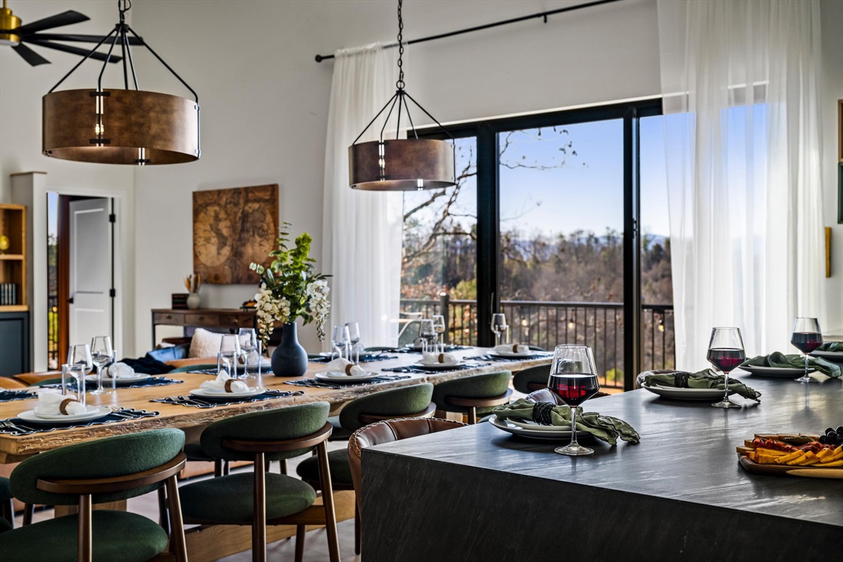 {Dining Room} Large indoor dining setup with seating for 16+, framed by natural light and mountain views — designed for memorable group meals.