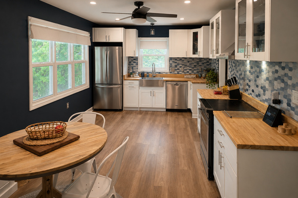 Bright open kitchen with butcher block countertops, stainless appliances and a casual dining table nearby.