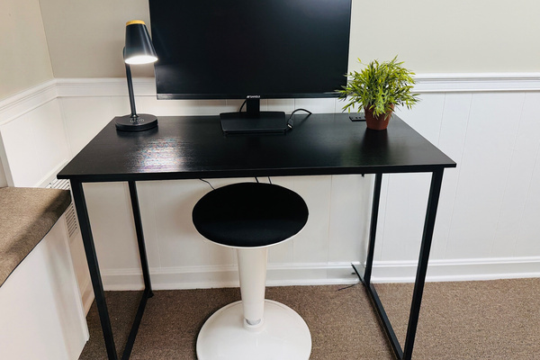 Dedicated workspace with a monitor, desk lamp, and comfortable task chair.