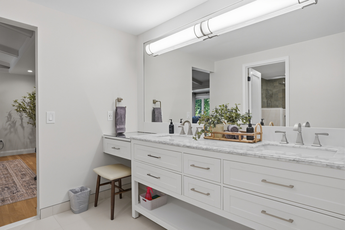 Bright, modern bathroom with a long double vanity, quartz countertop, and clean white cabinetry. Featuring a spacious mirror, sleek fixtures, and soft lighting, this bathroom offers a fresh, elegant, and hotel-like feel perfect for a comfortable stay.