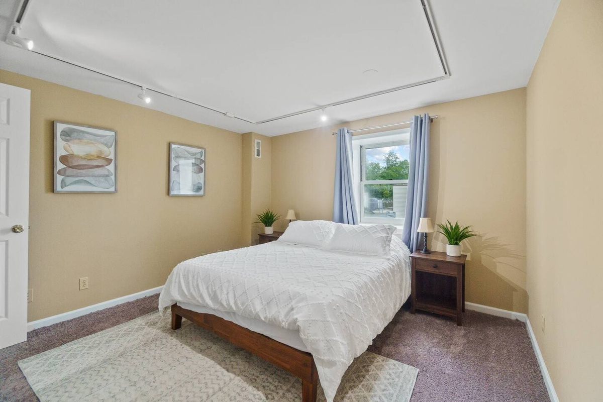 Spacious queen-sized bed with a large window, allowing natural light to fill the room and creating a bright, airy atmosphere.