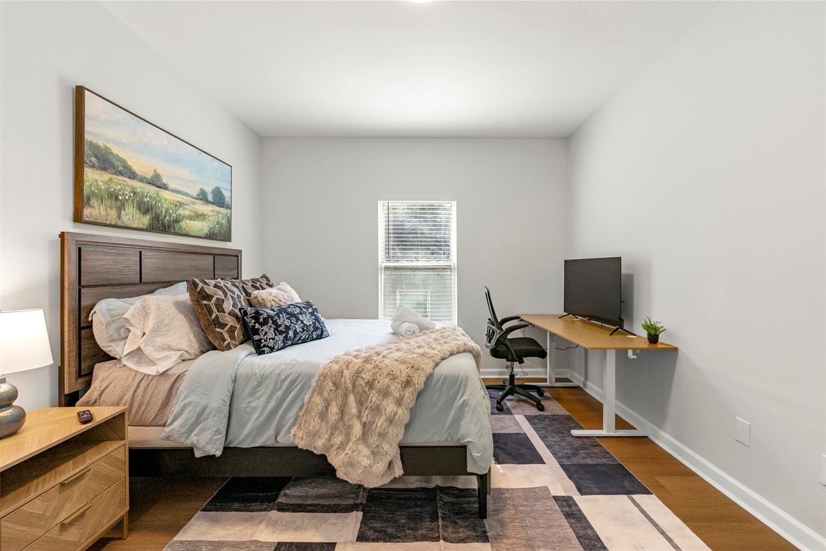 Inviting queen bedroom with workspace and plenty of natural light.