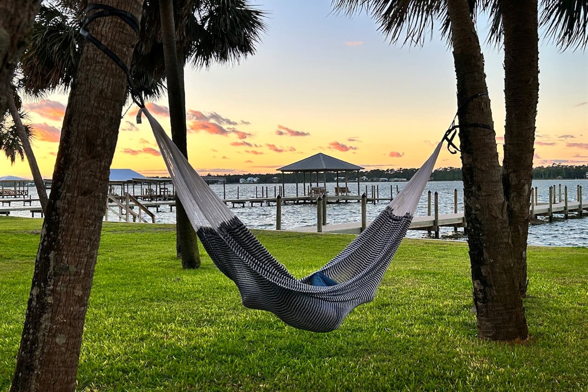 Unwind in a lakeside hammock under swaying palms, soaking in the golden sunset and serene water views.
