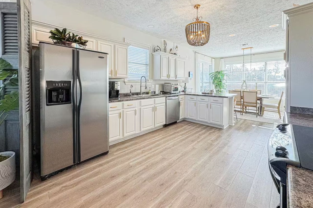 Airy kitchen with clean white finishes, wood-style flooring, and an open layout that connects effortlessly to the living space.