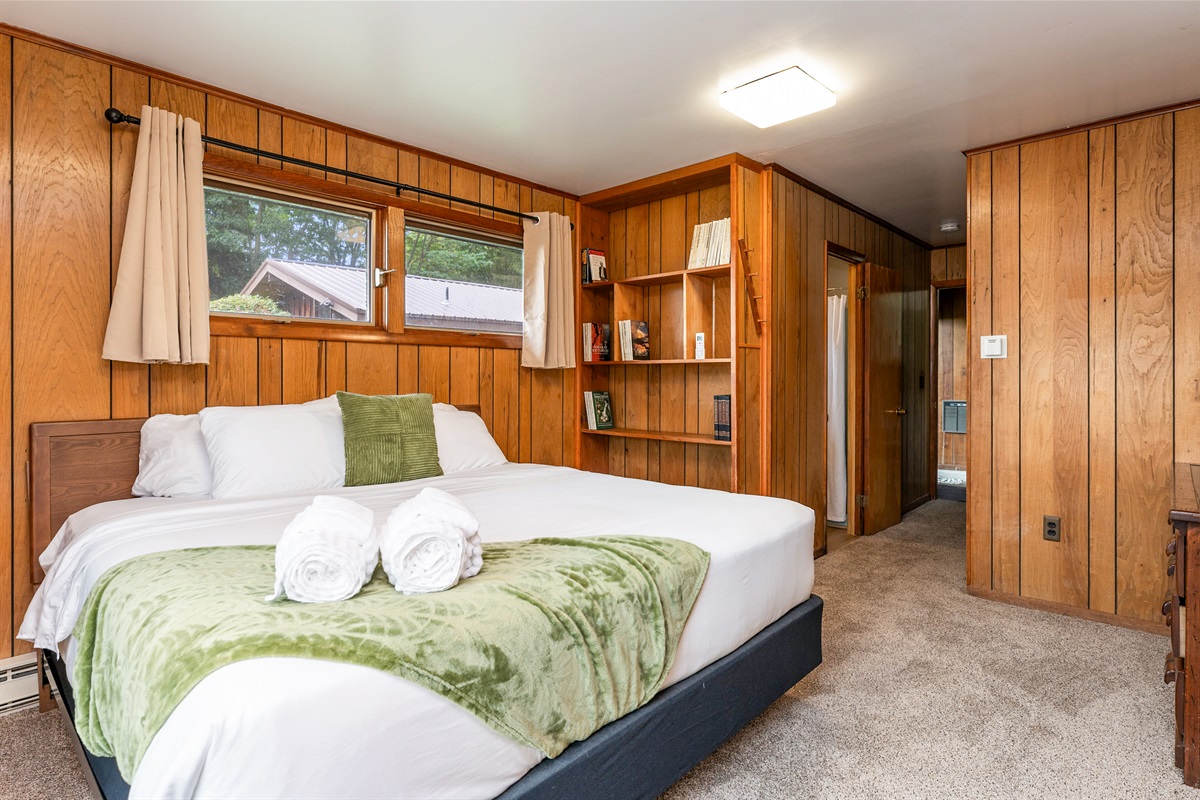 Charming bedroom complete with rustic paneling, built-in shelving, and a vintage dresser, blending comfort with character.