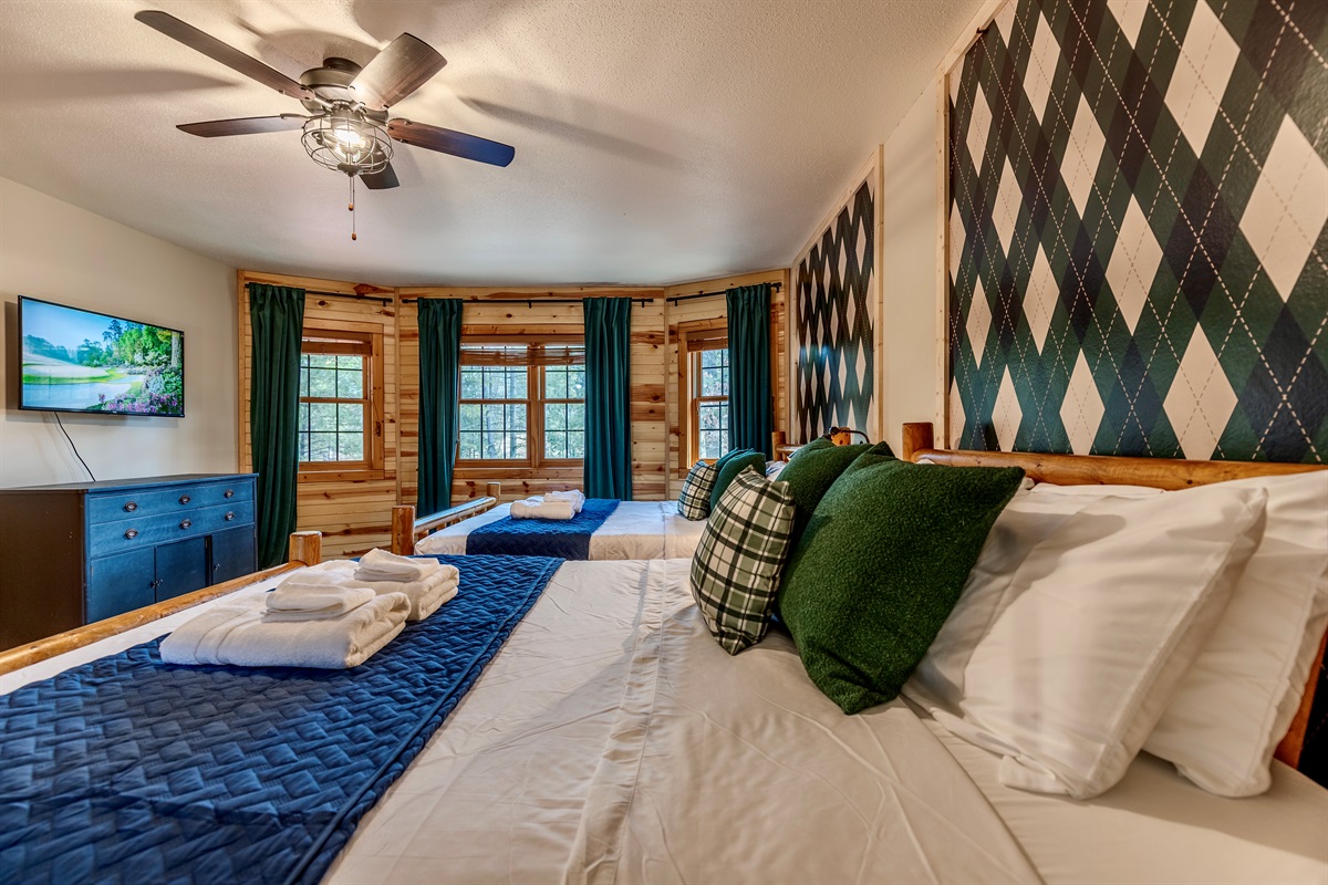 Upstairs bedroom with two queen beds and a twin over twin bed and smart TV.