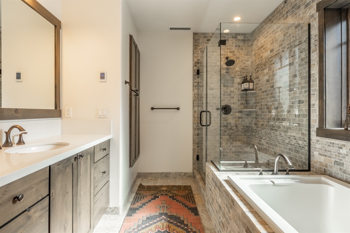 The primary en-suite bath feels like a private spa, with gorgeous tilework, a deep soaking tub, and a separate toilet room—designed for slow mornings and easy unwinding after a day on the mountain.