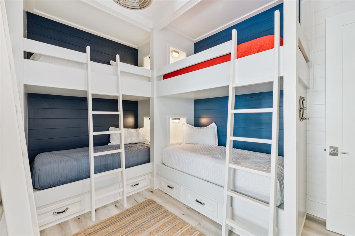 Second-floor bunk room featuring a smart- TV, closet, and six- spacious twin beds, each featuring its own storage nook, reading light, and USB port for charging devices.