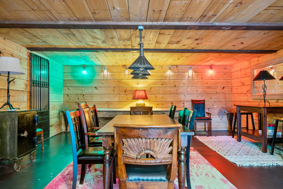 Descending into the "Below Deck" mess hall. Immersive green starboard and red port navigation lights cast a dramatic dual glow across the wood-planked dining room, illuminating the large family table and exposed timber beams for evening feasts.