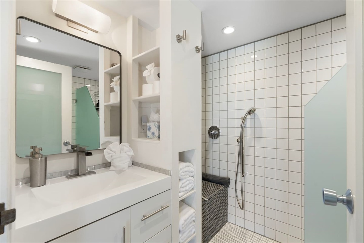 Modern bathroom featuring a sleek vanity, well-lit mirror, and a stylish walk-in shower with clean tile finishes — thoughtfully designed for both comfort and functionality