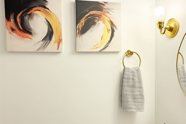 Stylish bathroom with hooks, framed art, and functional storage for towels or toiletries. 
