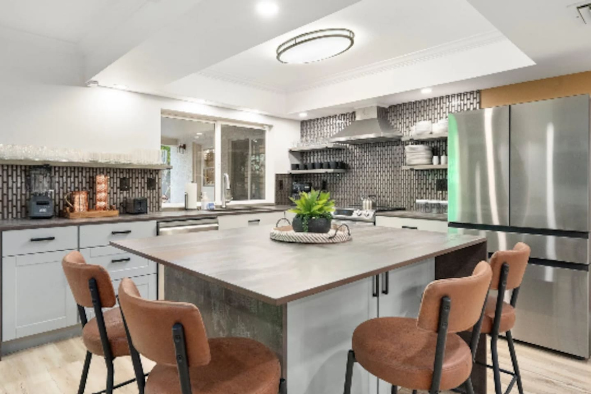 A spacious island with leather stools invites everyone to gather while the cook works their magic, with sleek stainless appliances rounding out the space.