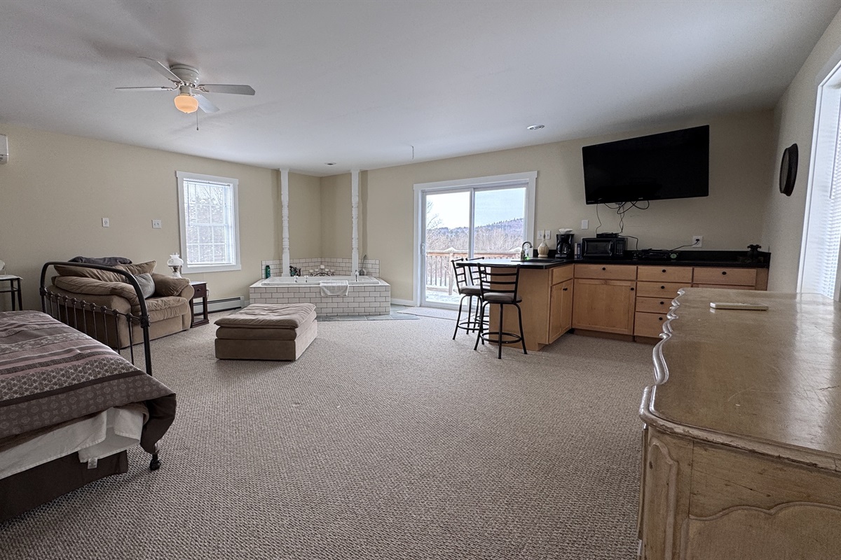 Primary bedroom with private wet bar, large stand-alone soaking tub, and access to private balcony 