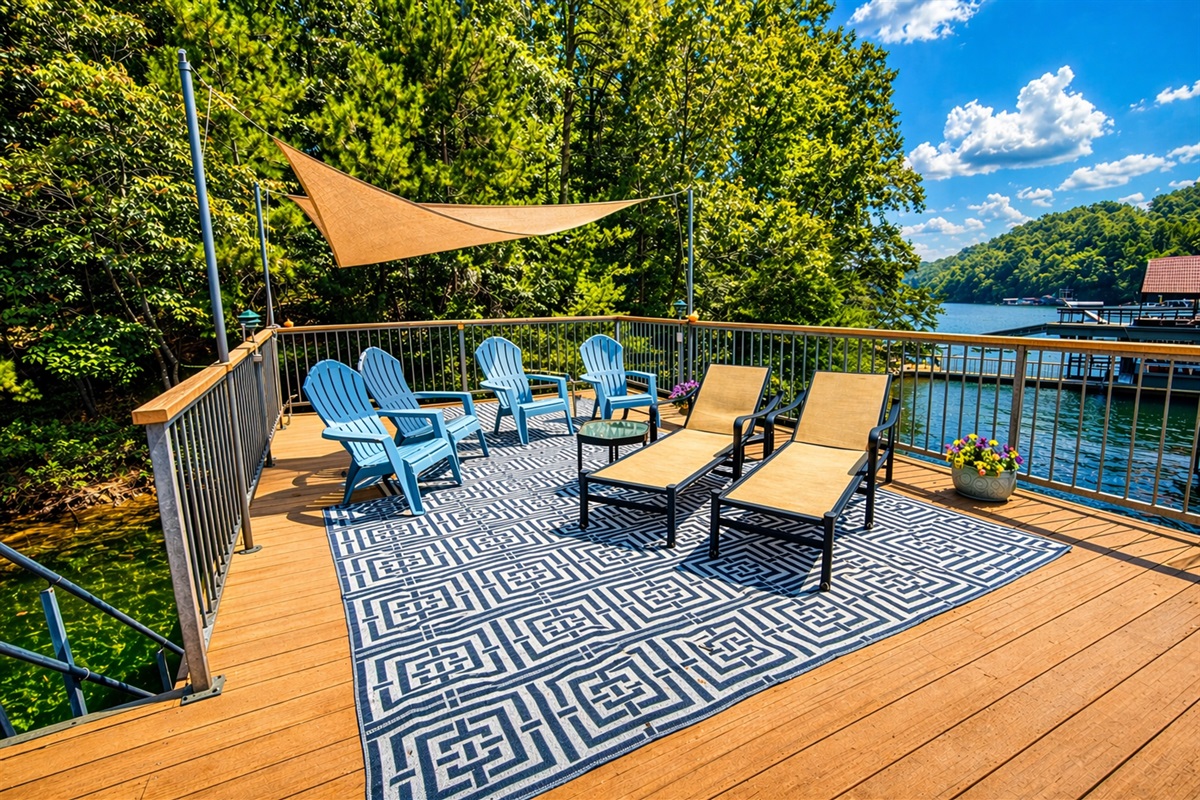 Spacious dock-top deck with shade sail, lounge chairs, and Adirondack seating overlooking the lake.