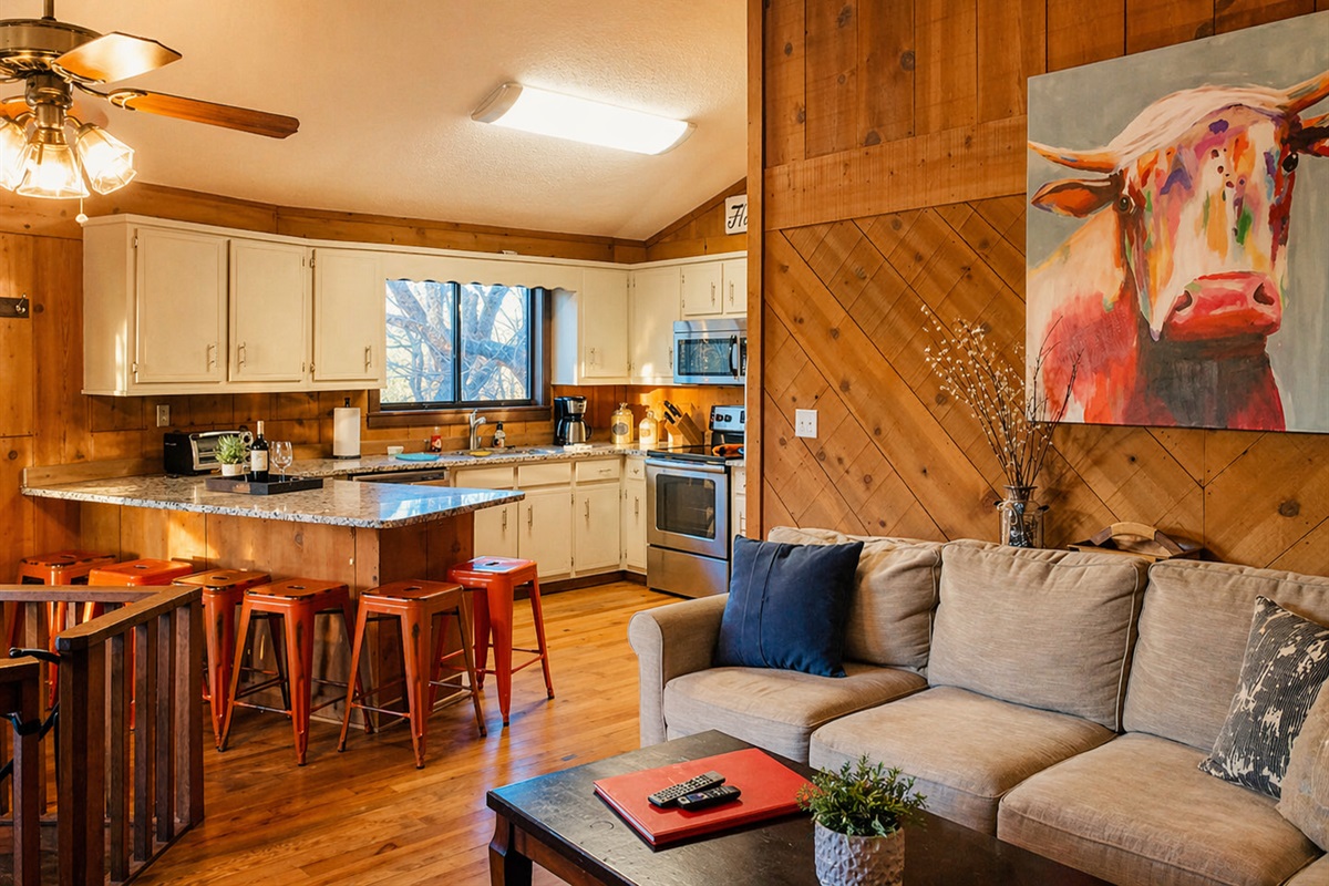 Warm wood tones, cozy seating, and a kitchen made for gathering—this is where mountain mornings start and memories are made with a stunning cow picture painted by our niece!