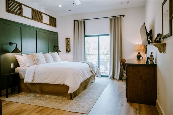 Rancher's Rest from the window side &mdash; pillow-top king, natural Hill Country light, and modern Western design upstairs at Gaines Ranch on the Square.