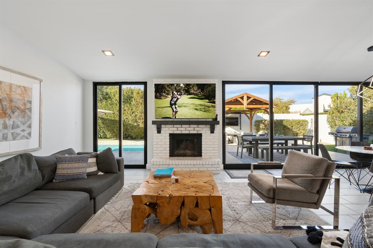 Cozy living area filled with natural light from large windows, offering a beautiful view of the pool.