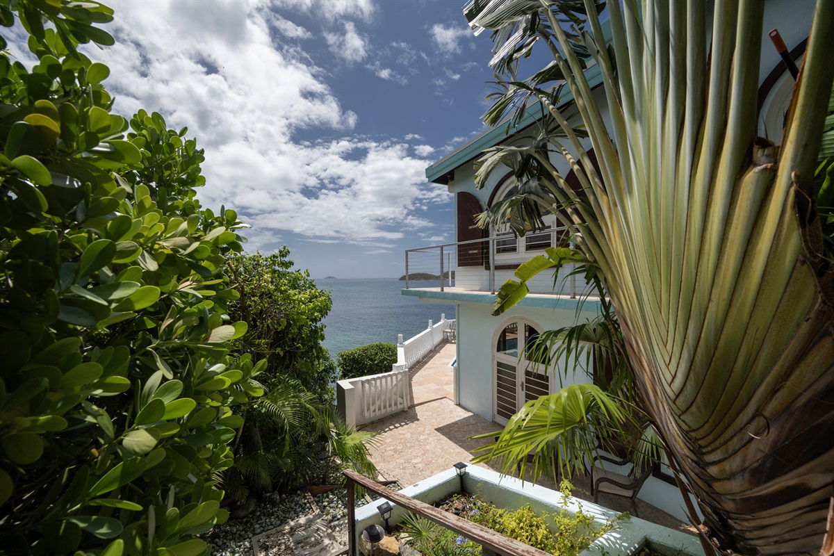 Lounge in style by the pool, surrounded by lush greenery and the sea.