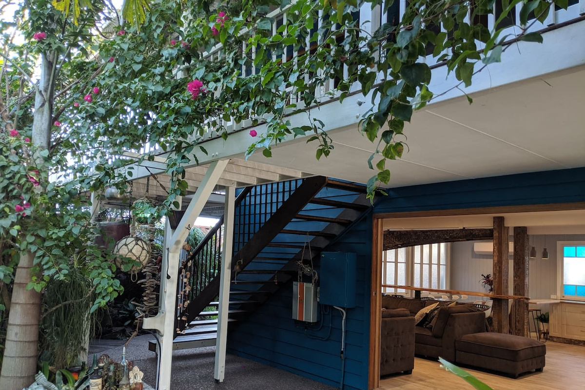 An external staircase links the upper and lower levels of Aaron's Beachside Boat House, with wide-opening doors connecting the downstairs living area to the garden.