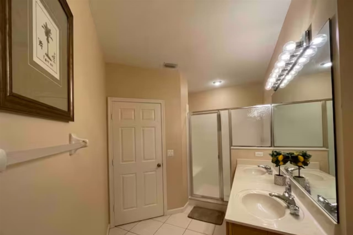 Bright bathroom with a large vanity, tile flooring, full mirror, and walk-in shower.