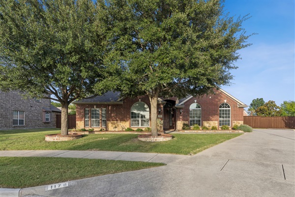 Beautifully landscaped front yard framed by mature shade trees. 