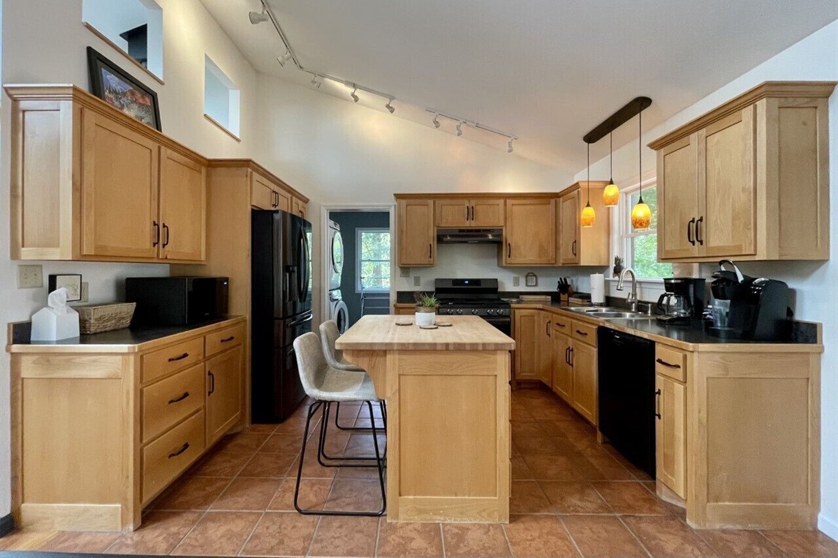 Fully stocked kitchen has new appliances,  door goes to the laundry, & back door