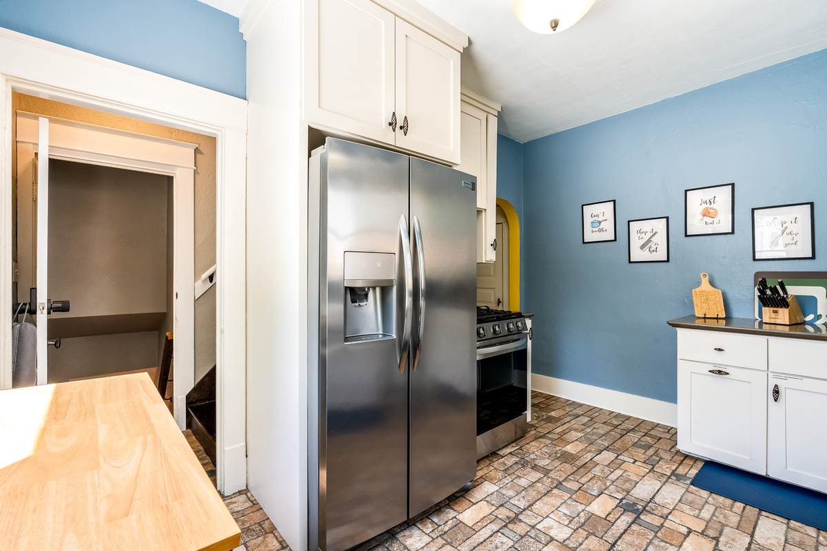 A true cook's kitchen featuring a premium gas range and ample stainless steel refrigeration. You'll find plenty of dishes, silverware, coffee cups, glasses, wine glasses and more for your group. The open door connects to the downstairs Garden Suite.