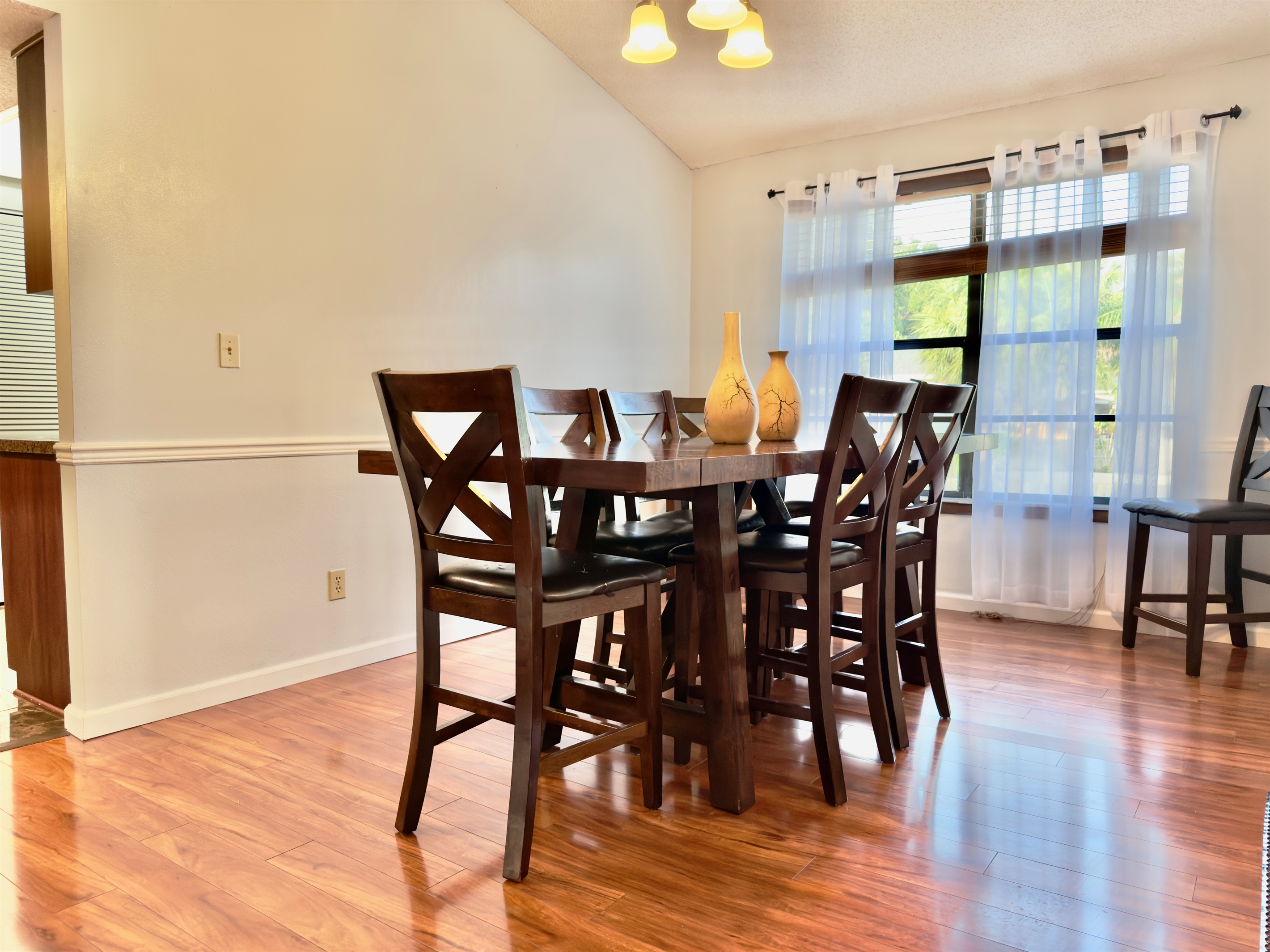 The rich, cherry-toned wood flooring creates a welcoming ambiance, while the adjoining wood-paneled accent wall adds warmth and texture.